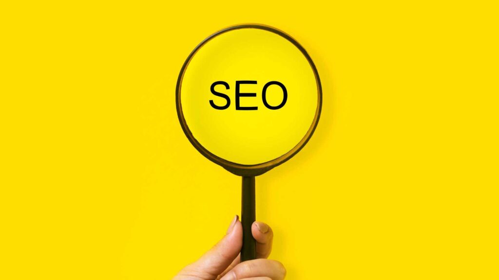 le mot "SEO" écrit sur un fond jaune avec une loupe devant